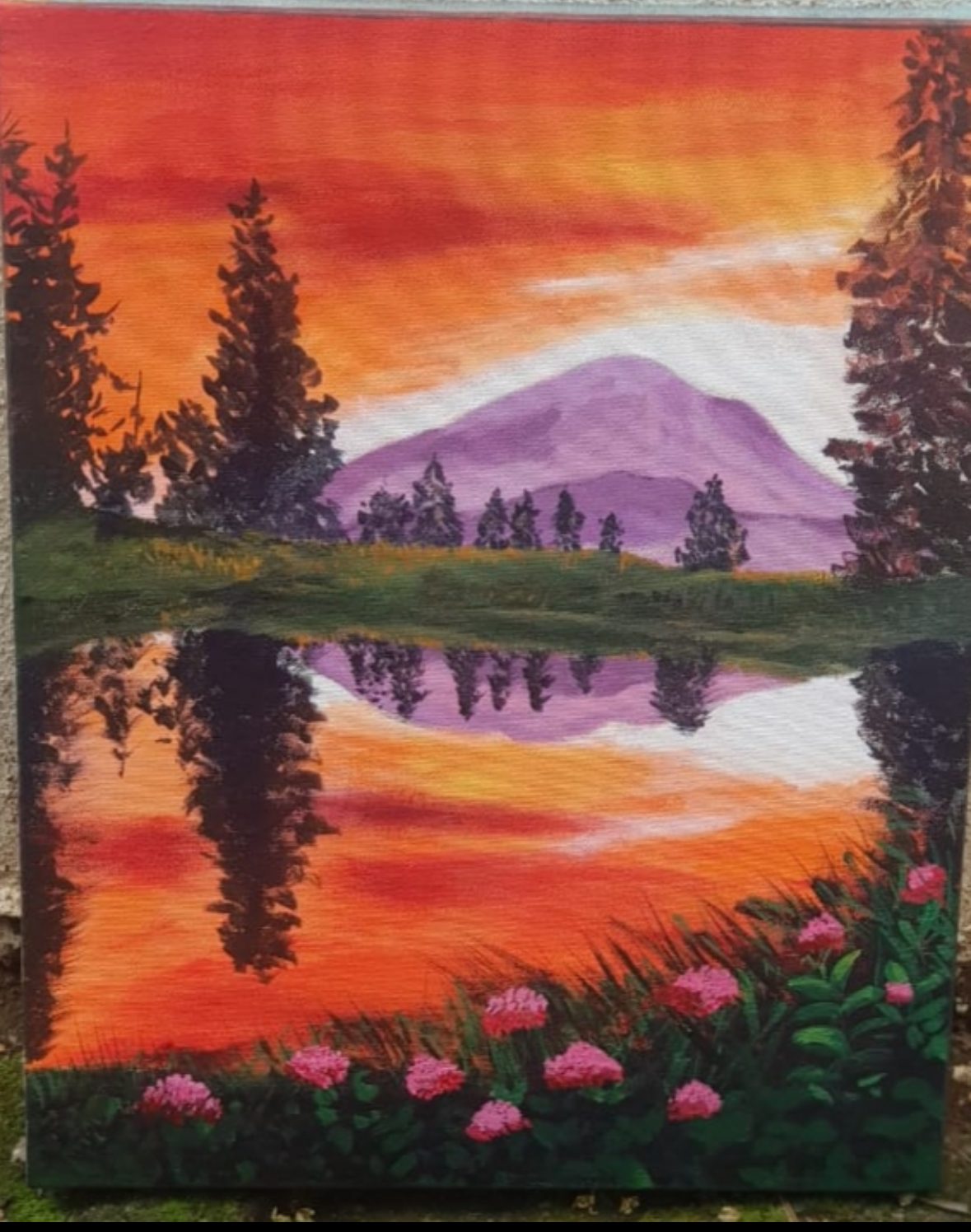 Mountain sunset reflected in water with pink flowers
