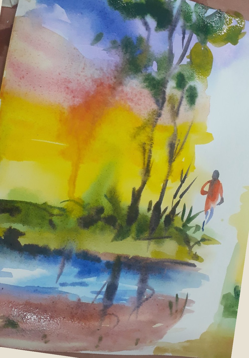 Figure walking by water at sunset